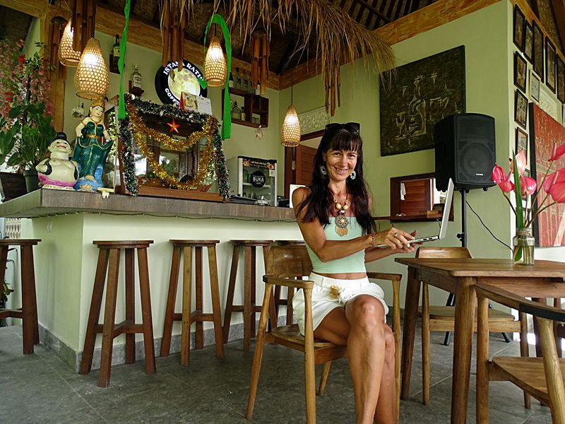 Woman sitting with a laptop inside Istana Ratih café in Sayan village near Ubud, Bali.