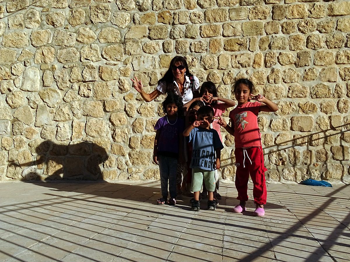 Woman posing with local children in the historic streets of Mardin, southeastern Turkey.